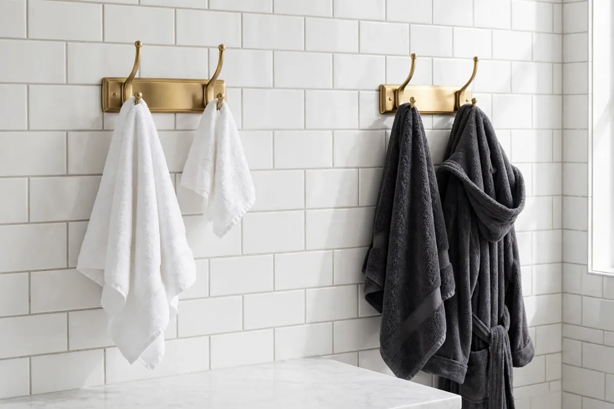 Two sets of double wall hooks in a bathroom holding towels and a bathrobe