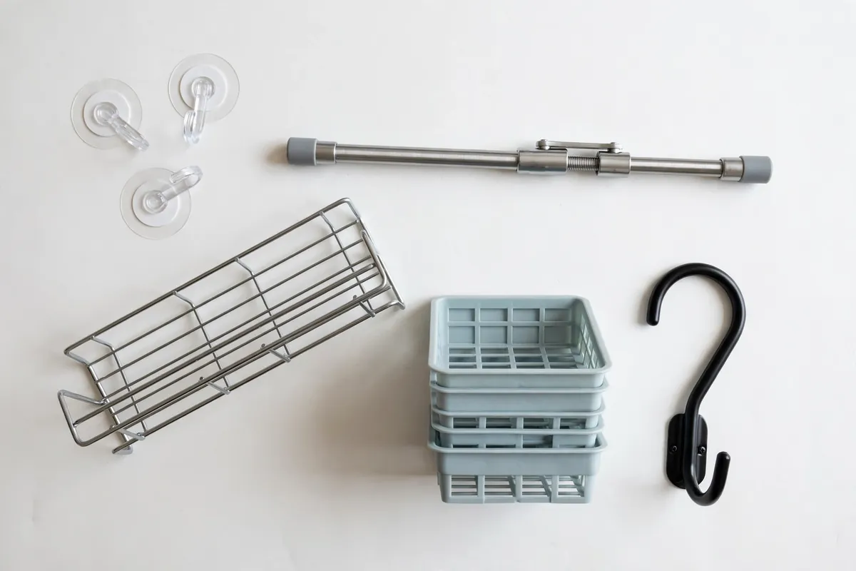 Budget kitchen organizers flat lay: adhesive hooks, tension rod, shelf riser, and bins