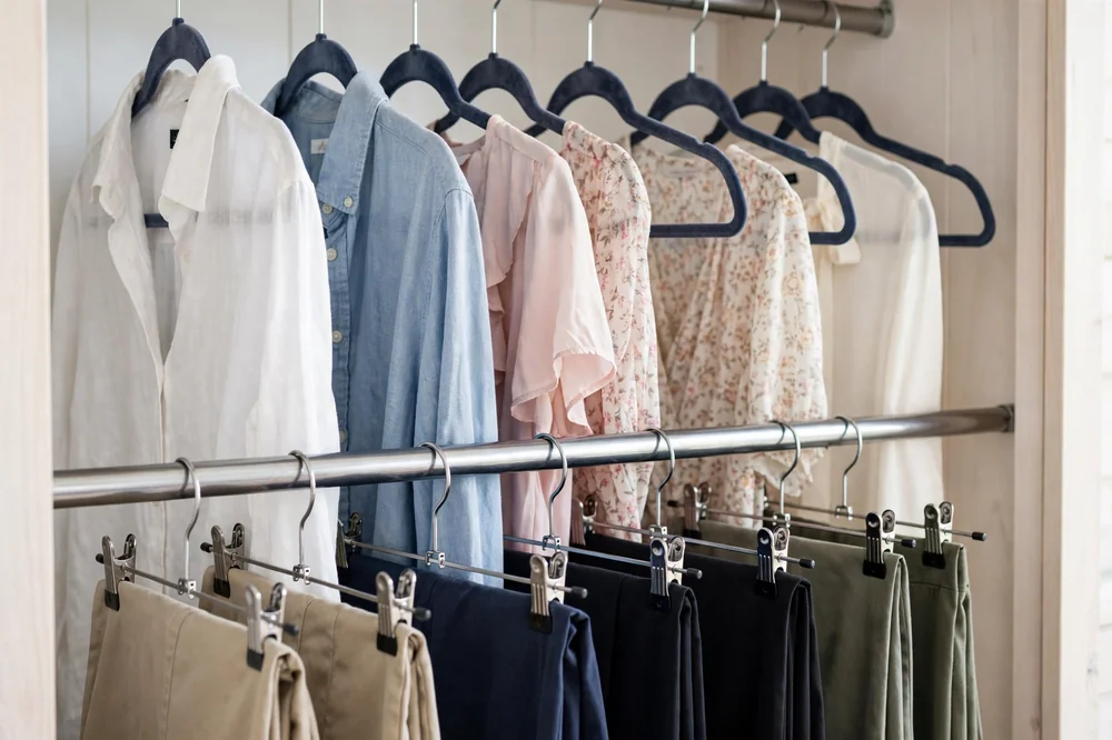 Close-up of double hanging rods in a small closet with shirts above and pants below on slim velvet hangers