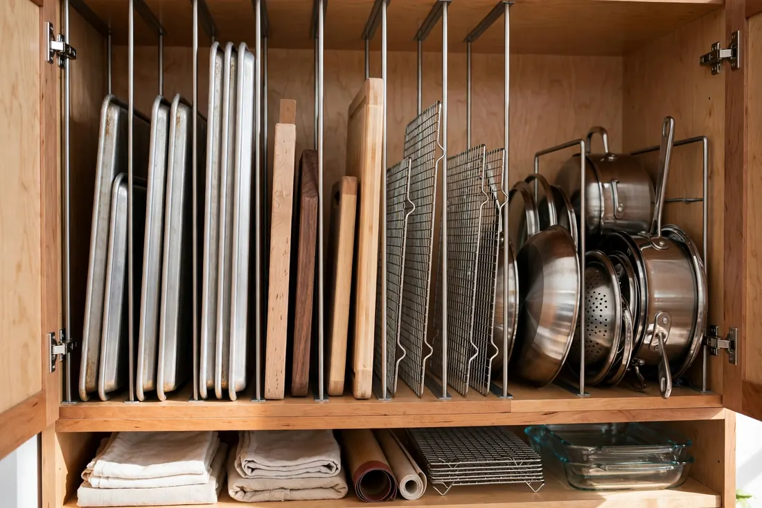Baking sheets and cutting boards stored upright in vertical dividers