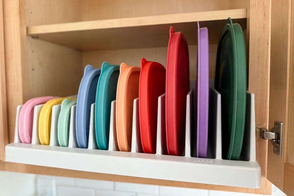 Plastic food container lids filed upright like records in a food container lid storage organizer, sorted by size
