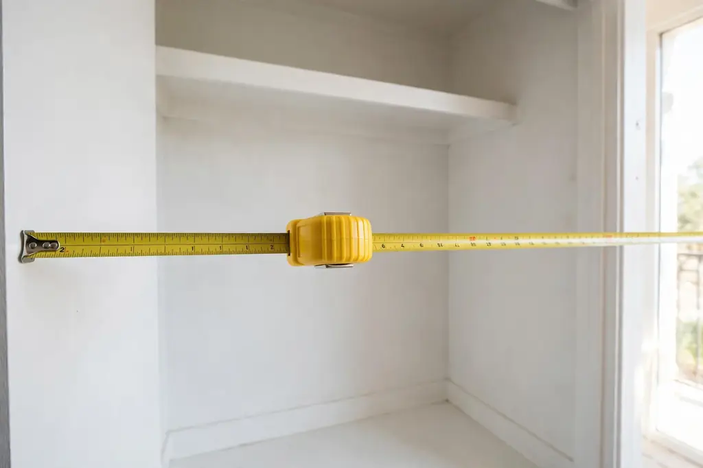 How to organize a closet with no shelves: measuring the bare closet width with a tape measure.