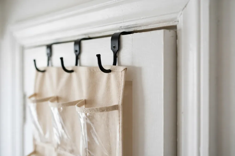 Over-door shoe organizer hooks on top of a white interior closet door