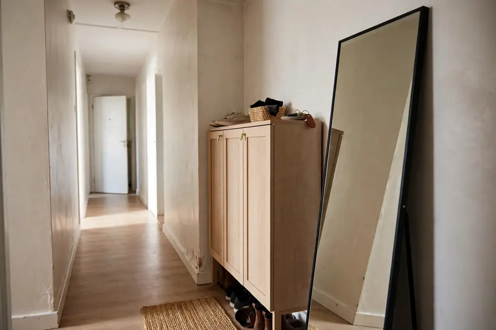Freestanding slim shoe cabinet and leaning mirror in a rental hallway