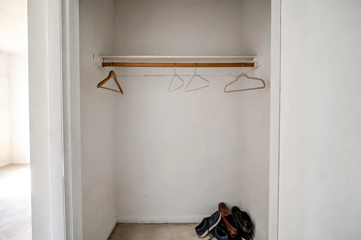 Small reach-in closet with one rod and empty unused space below it.