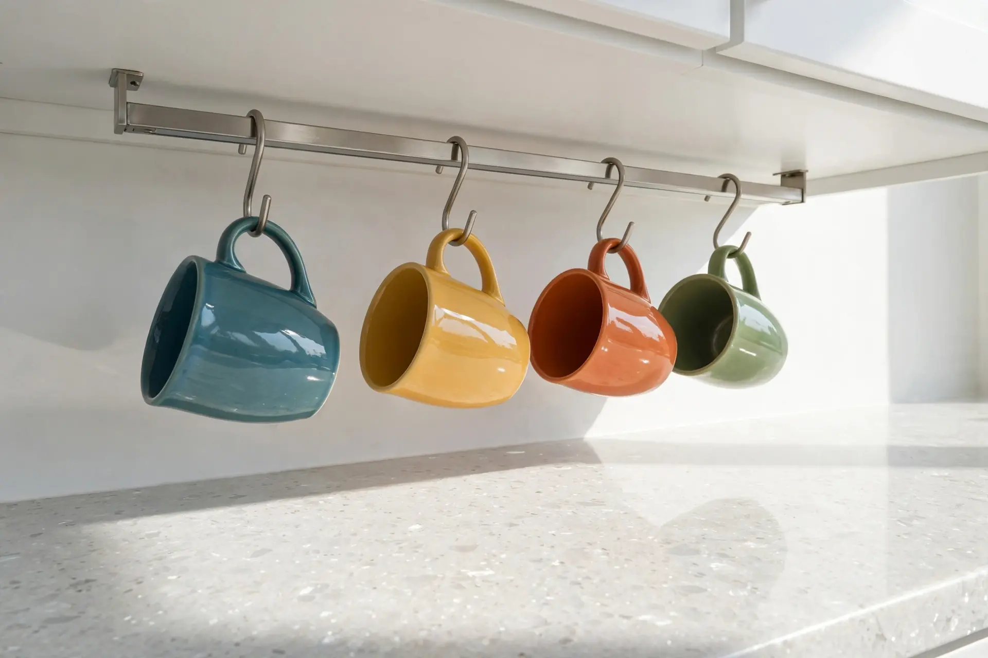 Mugs hanging from hooks mounted under a kitchen cabinet